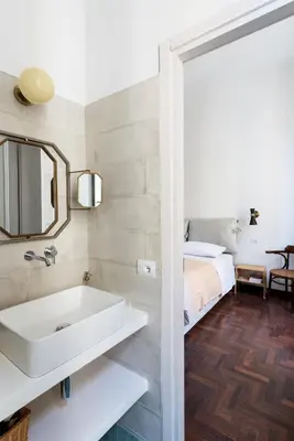 a bathroom with a sink and a mirror and a bed at Le Stanze di Margot con Parcheggio Privato in Rome