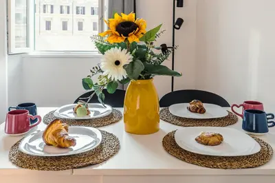 a table with plates of food and a vase with flowers at Domus Merulana 209 Colosseum Apt in Rome