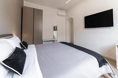 a bedroom with a white bed with a flat screen tv at Vatican Suites Apartment - Vatican City in Rome