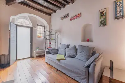 a living room with a gray couch and a window at Loft bohémien a Trastevere in Rome