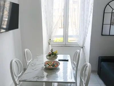 a dining table with white chairs and a bowl of candy at De Camillis Apartments in St Peter in Rome