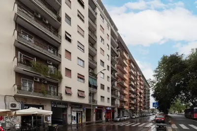 a tall white building on a city street at GuestHost - Cozy Ostiense Flat with Terrace! in Rome