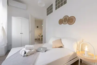 a white bedroom with a bed with a laptop on it at Trastevere 2Rooms with Balcony in Rome