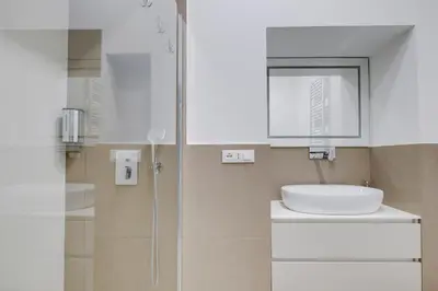 a white bathroom with a sink and a shower at Stunning 1BR, 2BATH Apartment in the Heart of Rome 6C in Rome