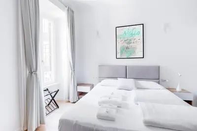 a white bedroom with a large white bed with white pillows at Charming Vatican Apartment with Balcony 6B in Rome