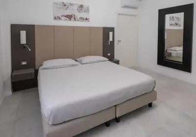 a bedroom with a large white bed and a mirror at Il Perugino Guest House in Rome