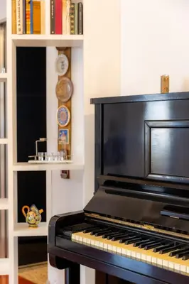 a black piano sitting in a room with books at Romano Apartments - 