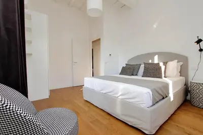 a white bedroom with a large bed and a chair at Torre Argentina in Rome