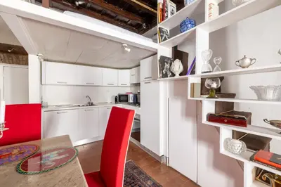 a kitchen with white cabinets and a table and red chairs at Elegant Studio in the Center in Rome