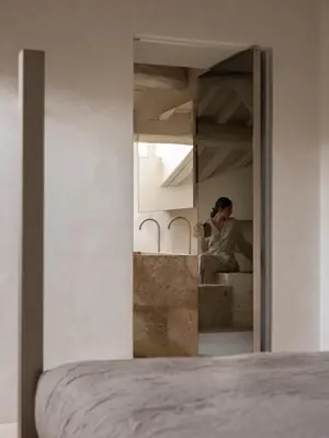 a woman sitting on a bed looking in a mirror at Nomos Hotel in Rome