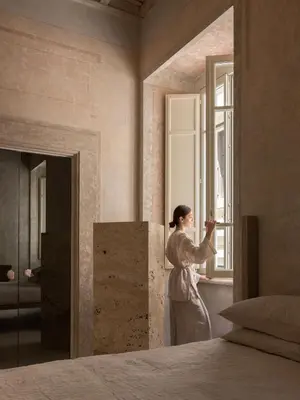 a woman standing in a room looking out a window at Nomos Hotel in Rome