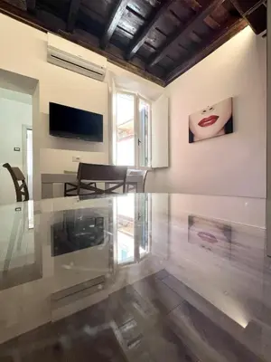 a living room with a glass table and a television at Spagna Home in Rome