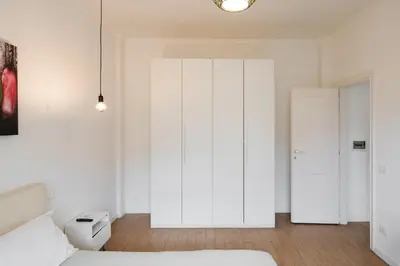 a white bedroom with a bed and a closet at Maison 46 in Rome