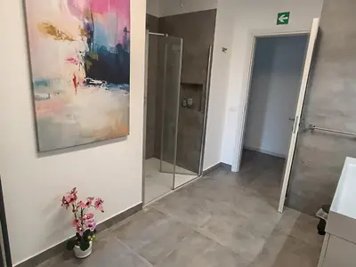 a bathroom with a painting on the wall and a vase with flowers at Casa Vacanze Bianca - Metro A - Furio Camillo in Rome
