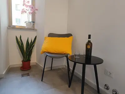 a table with a yellow pillow and a bottle of wine at Casa Vacanze Bianca - Metro A - Furio Camillo in Rome