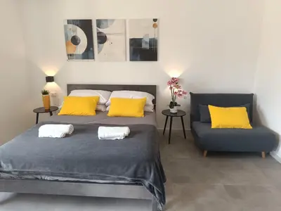 a bedroom with a bed with yellow pillows and a couch at Casa Vacanze Bianca - Metro A - Furio Camillo in Rome