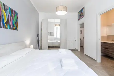 a white bedroom with a large white bed and a bathroom at Vatican Essence in Rome