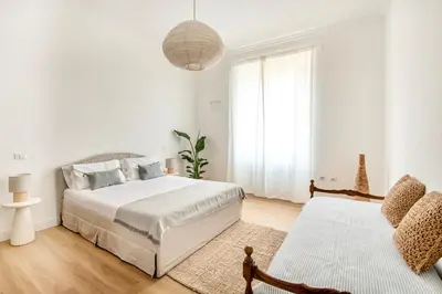 a white bedroom with two beds and a chair at Davìta - Casa Leda in Rome