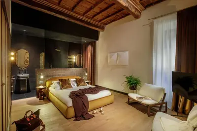 a bedroom with a large bed and a chair at Daplace - Palazzo Serpe Suites near Colosseum in Rome