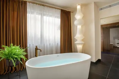 a bathroom with a large white tub in front of a window at Daplace - Palazzo Serpe Suites near Colosseum in Rome