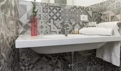 a white sink in a bathroom with tiles at Santonofrio Apartments Silver e White in Rome