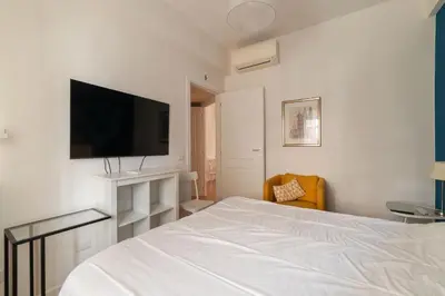 a bedroom with a white bed and a flat screen tv at GuestHost - Charming Apartment Metro Cipro in Rome