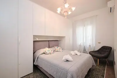 a bedroom with a bed with a chair and a chandelier at Residenza Lucis - Camillo Hospital - Monteverde by Hôtea in Rome