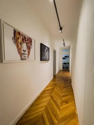 a hallway with white walls and wooden floors and paintings at Casa Alessandria in Rome