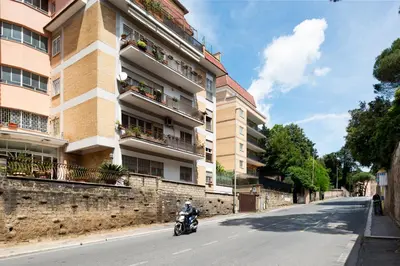 a man riding a motorcycle down a street next to a building at Vatican Loft - Mura Vaticane in Rome
