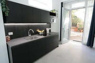 a kitchen with black cabinets and a sink at 1886 Colosseo Suite in Rome
