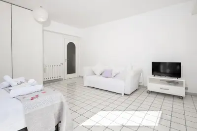a white living room with a couch and a tv at Margaret Guest House in Rome