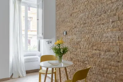 a vase of flowers on a table in a room with a brick wall at iFlat Vatican Modern & Comfortable Peaceful Gem in Rome
