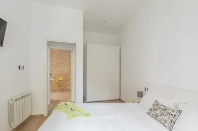 a white bedroom with two beds and a window at iFlat Vatican Modern & Comfortable Peaceful Gem in Rome