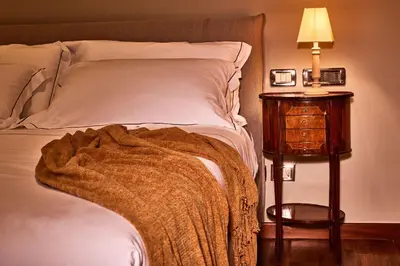 a bed with a blanket on it next to a night stand at TreasureRome Trevi Private Palazzo in Rome