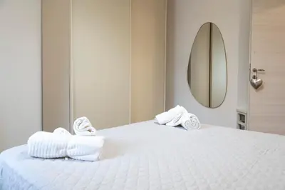 a white bed with towels on it with a mirror at Licia House - Intero Appartamento - San Giovanni in Rome
