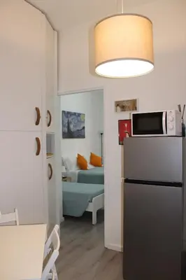 a kitchen with a refrigerator and a room with a bed at Cozy Home Medaglie d'Oro in Rome