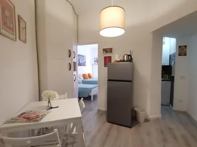 a kitchen and living room with a table and a refrigerator at Cozy Home Medaglie d'Oro in Rome