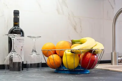 a bowl of fruit on a counter with a bottle of wine at Comfort House in Rome