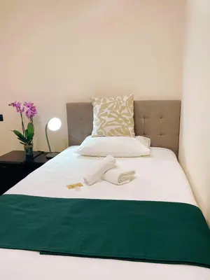 a bed with a green and white blanket on it at Laterano's House in Rome