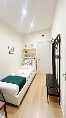a white bedroom with a bed and a table at Laterano's House in Rome