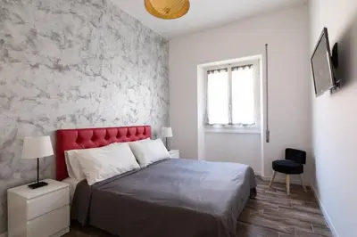 a bedroom with a bed with a red headboard and a window at La Dimora Arimondi in Rome