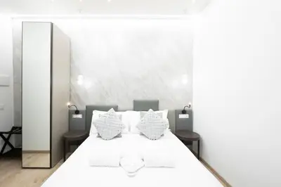 a bedroom with a white bed with a large mirror at Olimpico Luxury Rooms in Rome