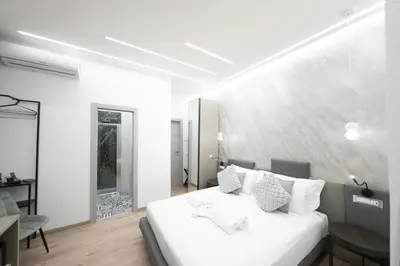 a white bedroom with a white bed and a table at Olimpico Luxury Rooms in Rome