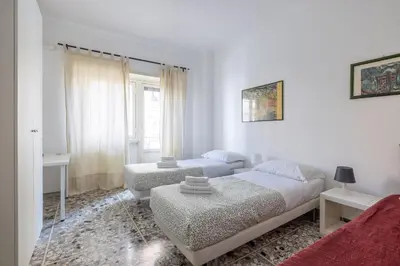 a white bedroom with two beds and a window at Atelier Latino in Rome