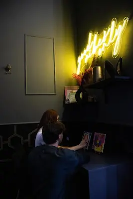 a man and a woman reading a book in a dark room at One of one experiences - ART ROOM in Rome