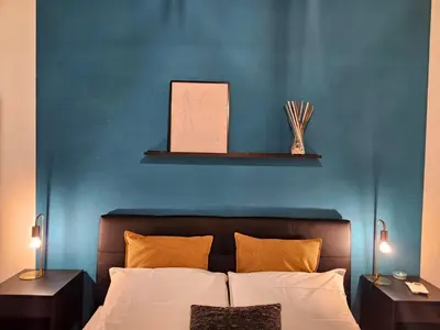 a bedroom with a blue wall and a bed with two tables at Be Your Home - Giulio's Apartment in Rome
