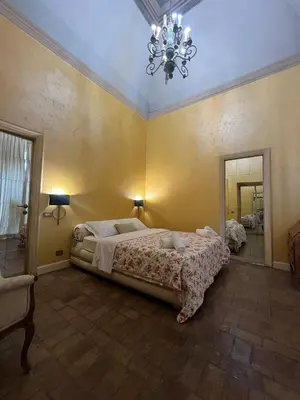 a bedroom with a large bed and a chandelier at Antico Suites Roma in Rome