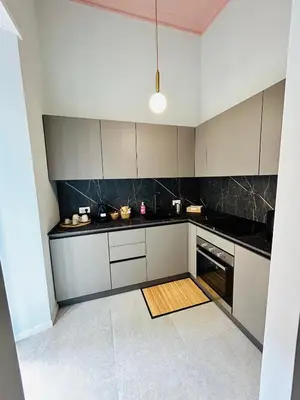 a kitchen with white cabinets and black counter tops at Aura Roma in Rome