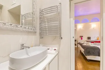 a white bathroom with a sink and a bedroom at Piazza Venezia appartamento con vista in Rome