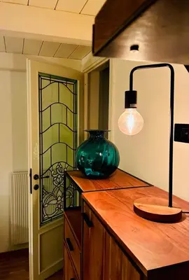 a green vase on a wooden counter with a lamp at CasaNa' in Rome
